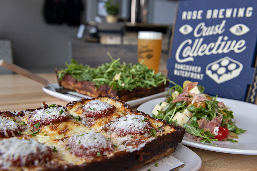 Ruse Brewing Crust Collective in Vancouver features Detroit-style pizza like the Quattro Cheesey pizza, foreground, and Towering Trees pizza, background, pictured with a glass of Papyrus Iris hazy IPA and antipasto salad.