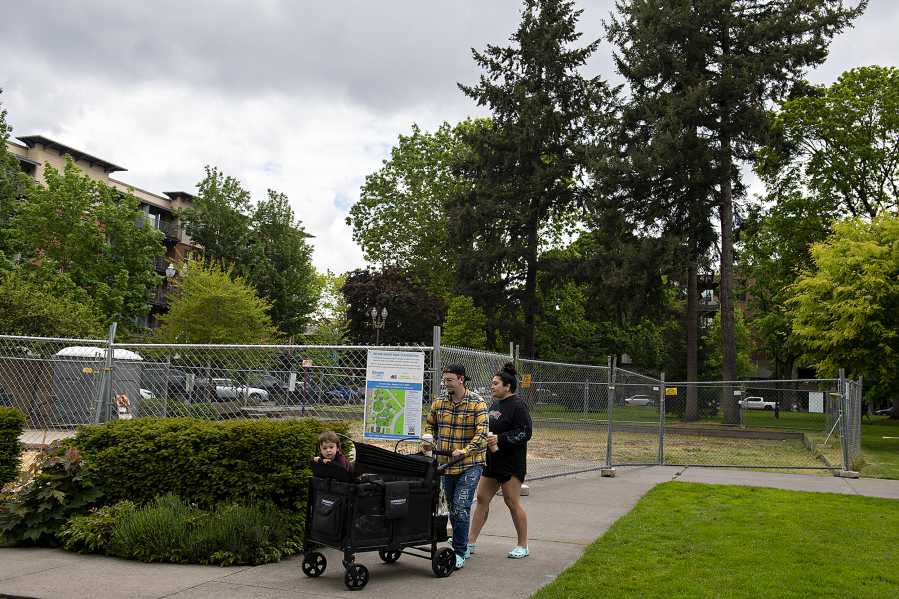 Atlas Shives, 2, of Vancouver, from left, joins his parents, Brendon and Lucia Shives, as they pass the Esther Short Park playground area Friday afternoon. Playground construction is scheduled to begin in June.