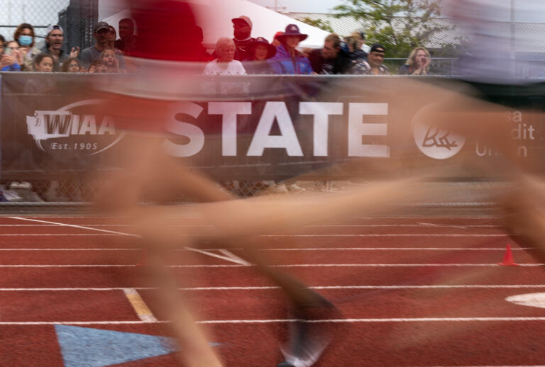 The 4A Girls 1600 field runs past a WIAA sign at the 2A/3A/4A State Track and Field Championships on Thursday, May 26, 2022, at Mount Tahoma High School in Tacoma.