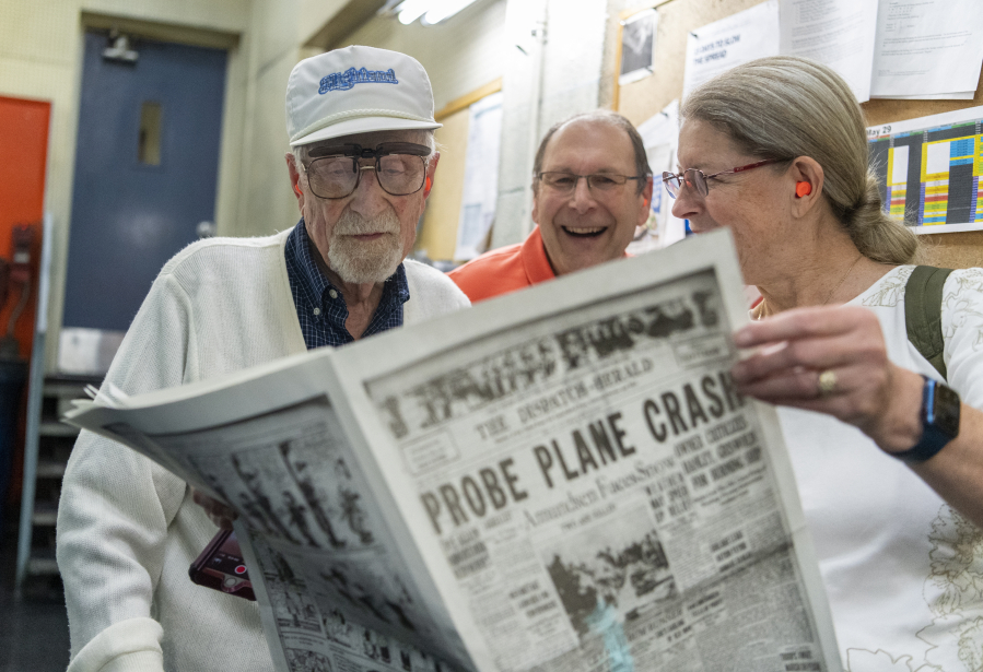 Frank Wallace, left, along with one of his sons John Wallace, center, and Deb Wallace look at a reproduction of a May 30, 1925 issue of The Dispatch-Herald of Erie, Pa. There were various stories plastered on its front page and, among them, had themes that would relate to his future career as someone who served in the Air Force during World War II.