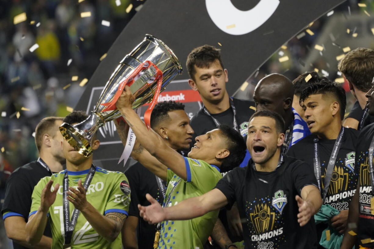 United States' Seattle Sounders forward Raul Ruidiaz holds the trophy alongside teammate midfielder Nicol?s Lodeiro after the Sounders defeated Mexico's Pumas to win the CONCACAF Champions League soccer final Wednesday, May 4, 2022, in Seattle. (AP Photo/Ted S.
