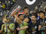 United States' Seattle Sounders forward Raul Ruidiaz holds the trophy alongside teammate midfielder Nicol?s Lodeiro after the Sounders defeated Mexico's Pumas to win the CONCACAF Champions League soccer final Wednesday, May 4, 2022, in Seattle. (AP Photo/Ted S.