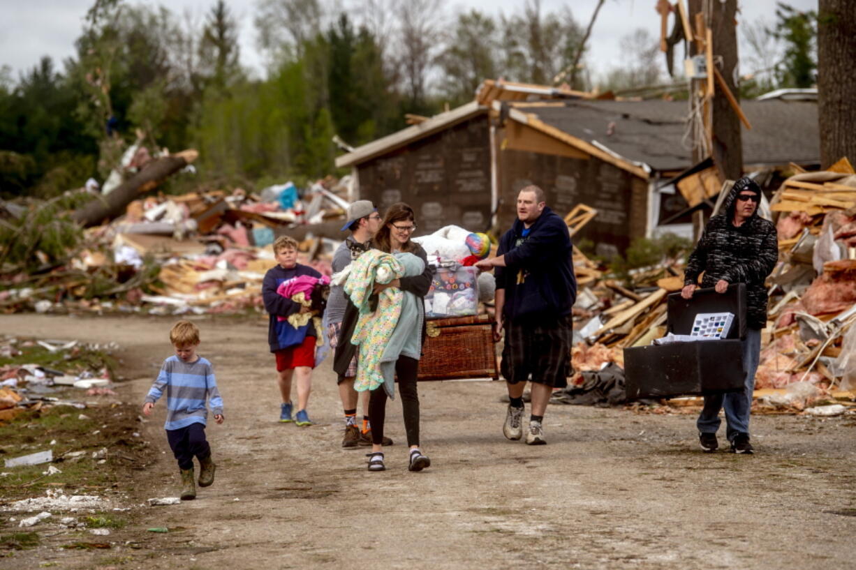 Resident Stephanie Kerwin, center, holds her baby Octavius in one arm and dog Pixie in the other as she and her family carry what they could salvage from her home in Nottingham Forest Mobile Home Park, Saturday, May 21, 2022, in Gaylord, Mich., following a tornado the day before. "This morning is when it first hit me...I could have lost people that I really love. I am so grateful," Kerwin said.