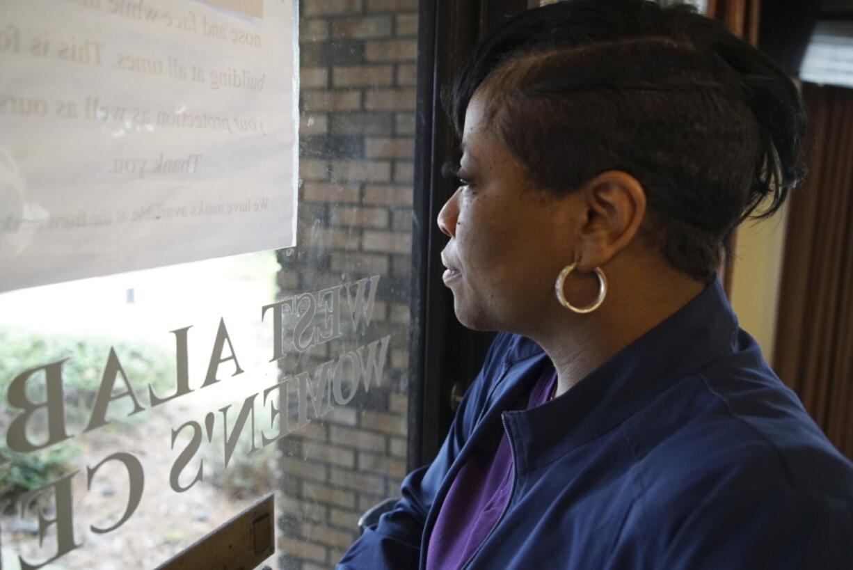 Alesia Horton, director of the West Alabama Women's Center in Tuscaloosa, Ala., looks out the window at protesters on Tuesday, March 15, 2022. A deeply religious woman, she says of those who picket the clinic: "God isn't theirs. God is all of ours." (AP Photo/Allen G.
