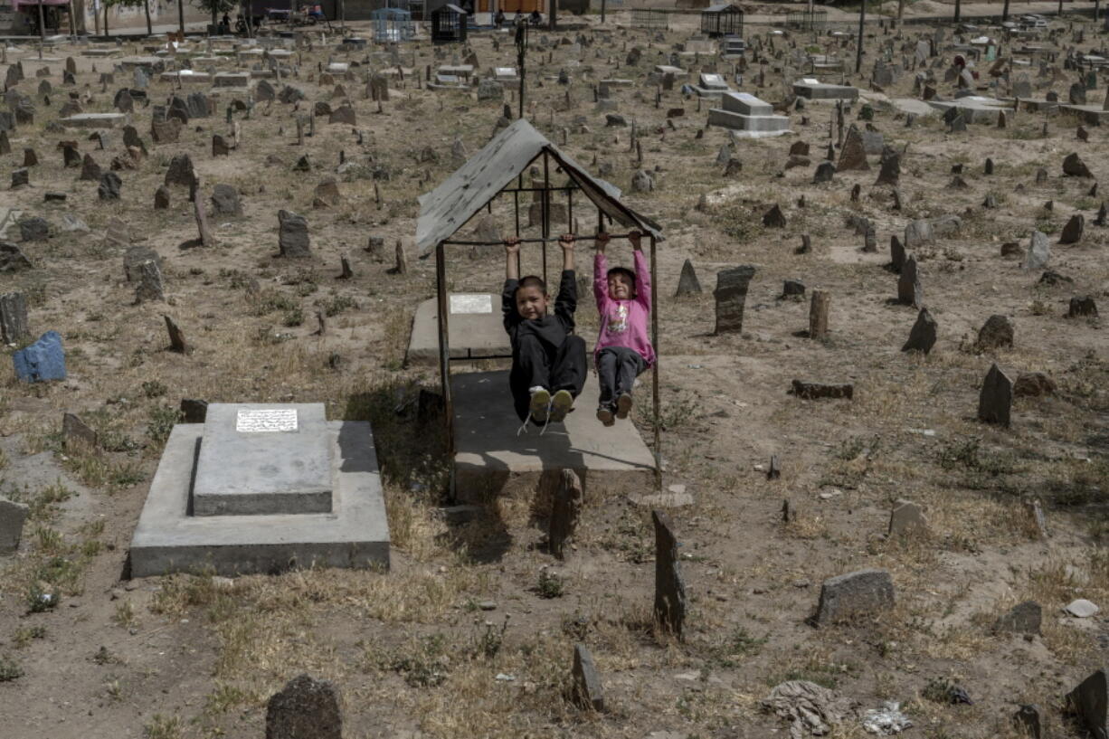 Afghan children play among the graves at a cemetery in Kabul, Afghanistan, Friday, May 27, 2022. There are cemeteries all over Afghanistan's capital, Kabul, many of them filled with the dead from the country's decades of war. They are incorporated casually into Afghans' lives. They provide open spaces where children play football or cricket or fly kites, where adults hang out, smoking, talking and joking, since there are few public parks.