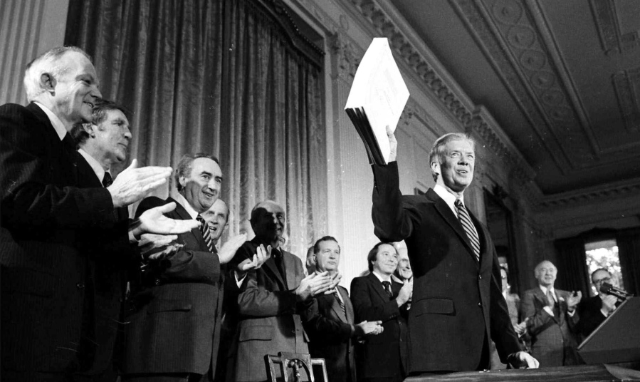 FILE - President Jimmy Carter holds up the Alaska National Interest Lands Conservation Act, which declared 104 million acres in Alaska as national parks, wildlife refuges and other conservation categories, after signing it into law at a ceremony at the White House in Washington, on Dec. 2, 1980. Carter on Monday, May 9, 2022, took the unusual step of weighing in on a court case involving his landmark conservation act and a remote refuge in Alaska.