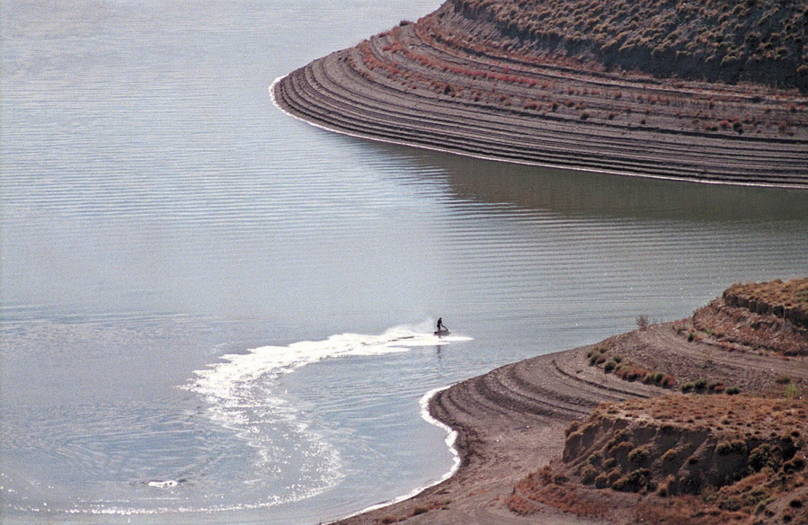 FILE - A man rides his personal water craft along the shore of Lake Pueblo, Colo., on Oct. 4, 1998. A boat capsized on a Colorado lake at night on Sunday, May, 29,2022, leaving one woman dead, 11 people hospitalized and one man missing.