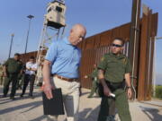 Homeland Security Secretary Alejandro Mayorkas, left, listens to Deputy patrol agent in charge of the US Border Patrol Anthony Crane as he tours the section of the border wall Tuesday, May 17, 2022, in Hidalgo, Texas.