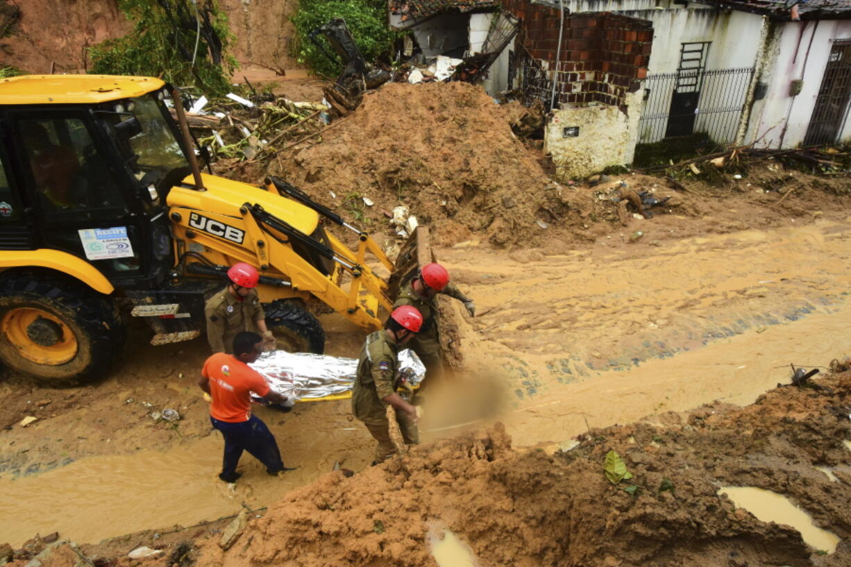 Firefighters carry a body recovered from a landslide triggered by heavy rain in the Jardim Monte Verde neighborhood of Recife in Pernambuco state, Brazil, Sunday, May 29, 2022. Landslides killed at least 84 people in the state of Pernambuco, according to authorities, and more than 1,000 people have been forced from their homes.