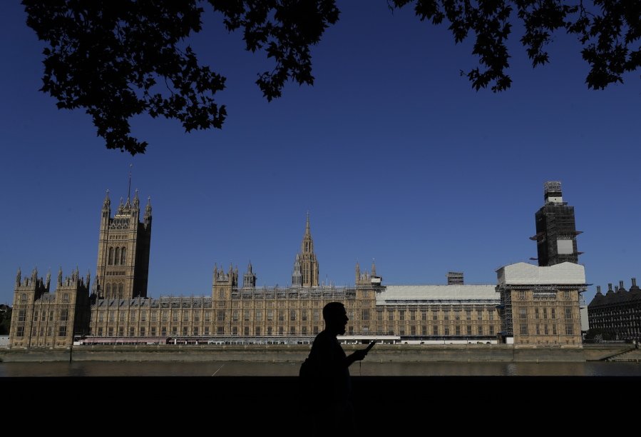 FILE - A pedestrian passes Britain's Houses of Parliament on the bank of The River Thames in London, Aug. 29, 2019. A U.K. Conservative lawmaker has been released on bail while police investigate allegations of rape and sexual assault against him. The legislator was arrested Tuesday May 17, 2022, on suspicion of indecent assault, sexual assault, rape, abuse of position of trust and misconduct in public office.