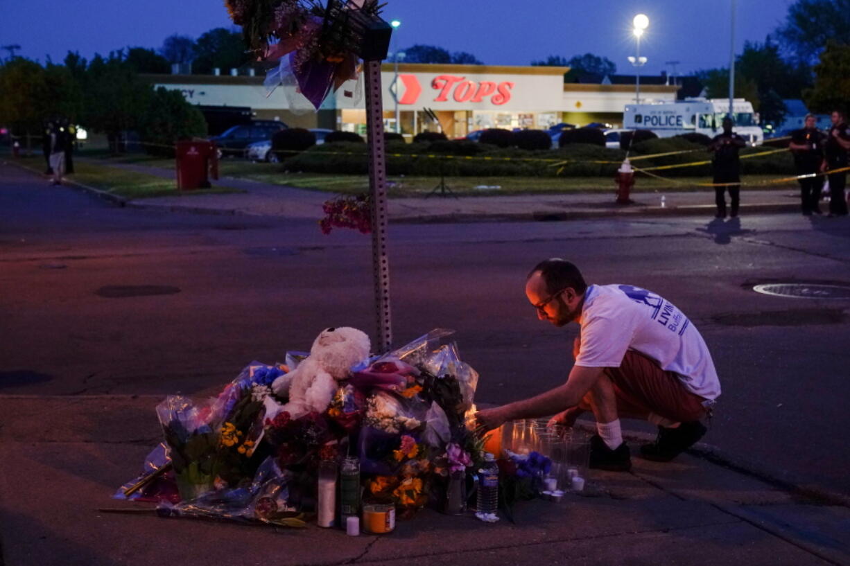 FILE - A person pays his respects at a makeshift memorial outside the scene of a shooting at a supermarket in Buffalo, N.Y., Sunday, May 15, 2022.