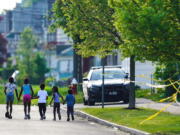 FILE - Children walk hand-in-hand near the scene of a shooting at a supermarket in Buffalo, N.Y., May 15, 2022. The shooting rampage at a Buffalo supermarket, carried out by an 18-year-old who was flagged for making a threatening comment at his high school the year before, highlights concerns over whether schools are adequately supporting and screening students.