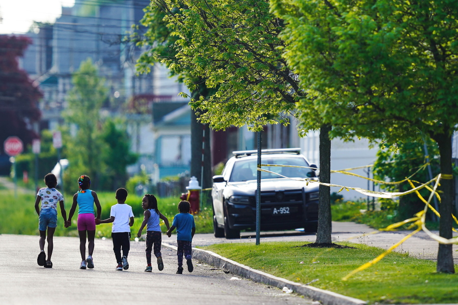 FILE - Children walk hand-in-hand near the scene of a shooting at a supermarket in Buffalo, N.Y., May 15, 2022. The shooting rampage at a Buffalo supermarket, carried out by an 18-year-old who was flagged for making a threatening comment at his high school the year before, highlights concerns over whether schools are adequately supporting and screening students.