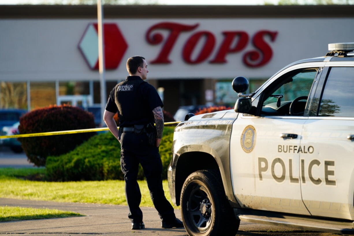 A police officer stands guard outside the scene of a shooting at a supermarket, in Buffalo, N.Y., Sunday, May 15, 2022.