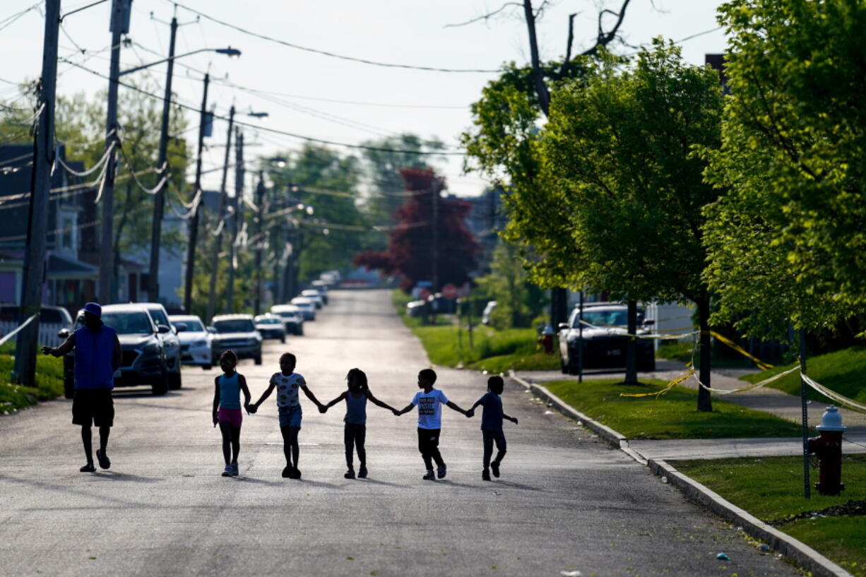 FILE - Children walk hand in hand in a street near the scene of a shooting at a supermarket in Buffalo, N.Y., Sunday, May 15, 2022. Long before an 18-year-old avowed white supremacist inflicted terror at a Buffalo supermarket, the city's Black neighborhoods, like many others around the nation, had been dealing with wounds that are generations old.