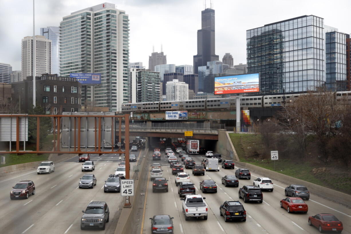 FILE - Traffic flows along Interstate 90 highway as a Metra suburban commuter train moves along an elevated track in Chicago on March 31, 2021.   With upcoming data showing traffic deaths soaring, the Biden administration is steering $5 billion in federal aid to cities and localities to address the growing crisis by slowing down cars, carving out bike paths and wider sidewalks, and nudging commuters to public transit.