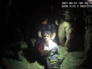 In this image from body camera video provided by Sedgwick County, police put Cedric "C.J." Lofton, 17, into a body-length restraining device called a WRAP outside his home in Wichita, Kan., on Sept. 24, 2021. His foster father, unable to deal with a teen who seemed to be in the throes of schizophrenia, had called Wichita police. When they arrived, Cedric refused to leave the porch and go with them; he was obstinate but afraid, meek but frantic.