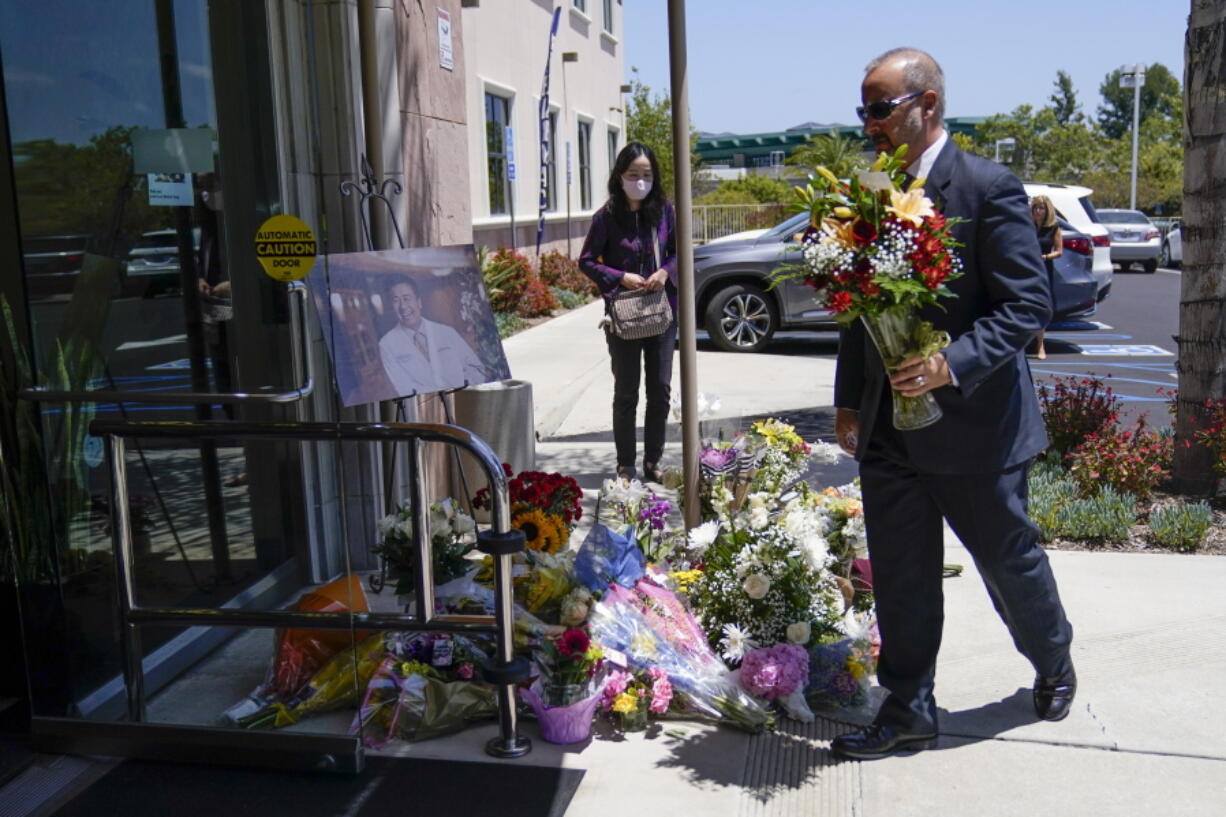 A man places flowers at a memorial honoring Dr. John Cheng sits outside his office building on Tuesday, May 17, 2022, in Aliso Viejo, Calif. Cheng, 52, was killed in Sunday's shooting at Geneva Presbyterian Church.