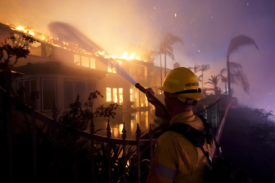 A firefighter works to put at a structure burning during a wildfire Wednesday, May 11, 2022, in Laguna Niguel, Calif. (AP Photo/Marcio J.