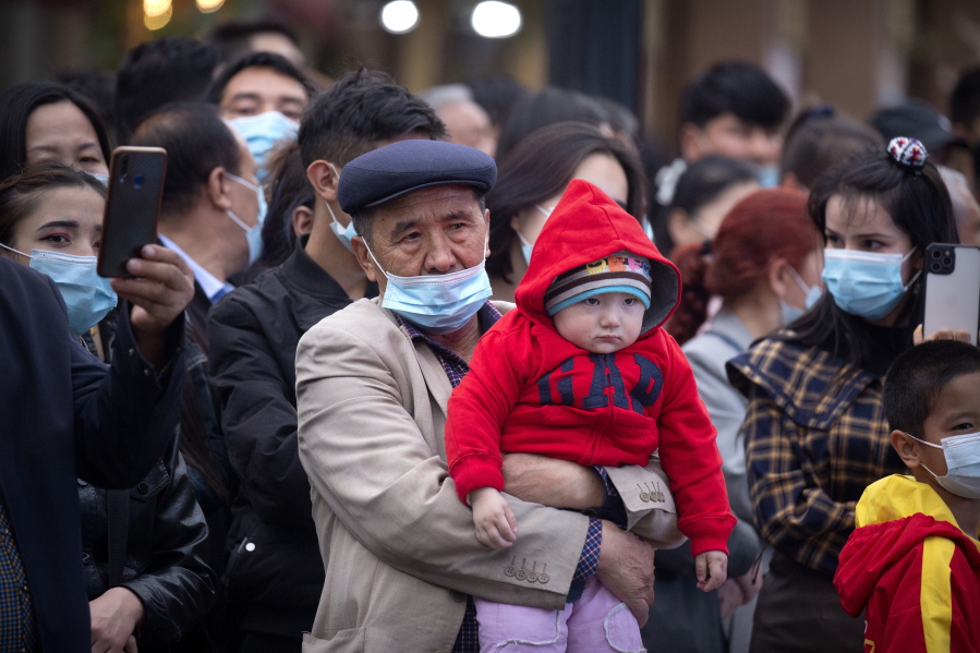 FILE - A man holds a child as they watch a dance performance at the International Grand Bazaar in Urumqi in western China's Xinjiang Uyghur Autonomous Region on April 21, 2021. Allegations of human rights abuses in China's northwestern Xinjiang region are the dominant issue on a visit by the United Nations' top rights official that starts Monday, May 23, 2022. changes are needed to fight Islamic extremism.
