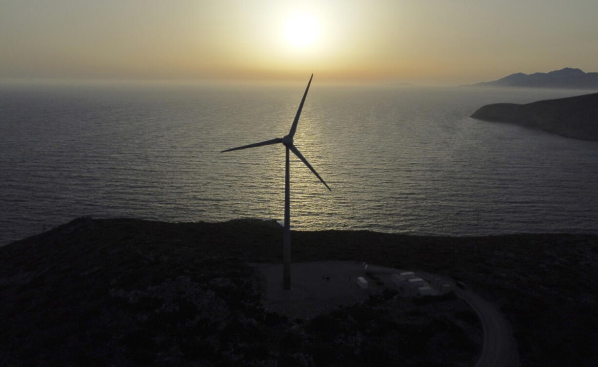 The sun sets behind a wind turbine on the Aegean Sea island of Tilos, southeastern Greece, Monday, May 9, 2022. When deciding where to test green tech, Greek policymakers picked the remotest point on the map, tiny Tilos. Providing electricity and basic services, and even access by ferry is all a challenge for this island of just 500 year-round inhabitants. It's latest mission: Dealing with plastic.