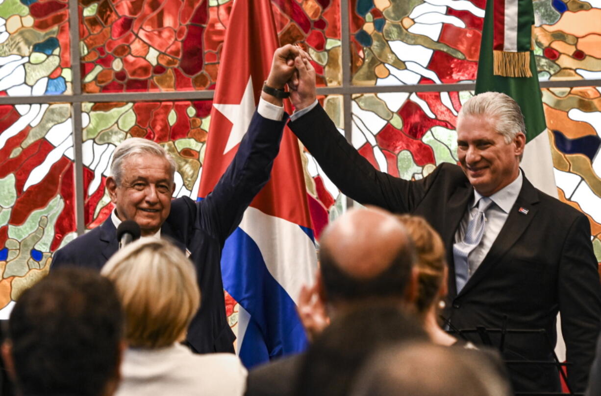 Cuban President Miguel Diaz Canel, right, and his Mexican counterpart Andres Manuel Lopez Obrador, left, raise their arms during a ceremony to award the Jose Marti order to President Lopez Obrador, at Revolution Palace in Havana, Cuba, Sunday, May 8, 2022.