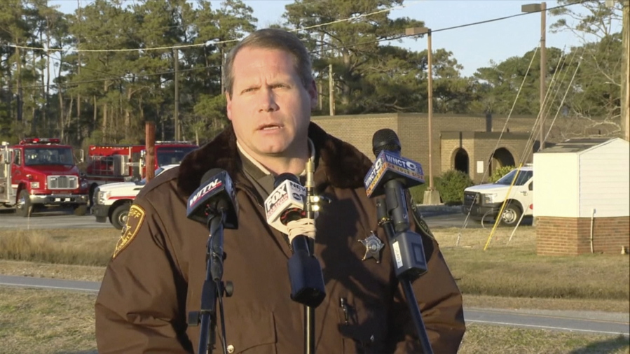 FILE - Carteret County Sheriff Asa Buck speaks with reporters in Carteret County, N.C., on Monday, Feb. 14, 2022.  The families of four people - including three teens - who died in a February plane crash off the North Carolina coast are suing the companies that owned the plane and employed the pilot, who also died. The suit claims the pilot failed to properly fly the single-engine plane in weather conditions with limited visibility, making the firms liable.
