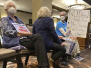 Community members opposed to a proposal to build a $1.4 billion desalination plant in Huntington Beach sit with signs at a California Coastal Commission hearing in Costa Mesa, Calif., Thursday May 12, 2022. For more than two decades, California's Orange County has debated whether to build a seaside plant to convert the Pacific Ocean's salt water into drinking water in hopes of buffering against droughts like the one now gripping the nation's most populous state.