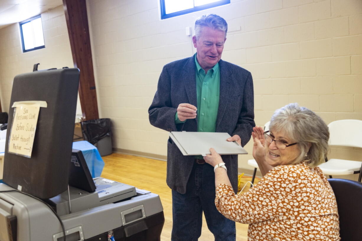 Idaho Gov. Brad Little laughs as he takes an "I Voted" sticker from poll worker Carla Stark after casting his ballot in Idaho's Primary Election in Emmett, Idaho, Tuesday, May 17, 2022.