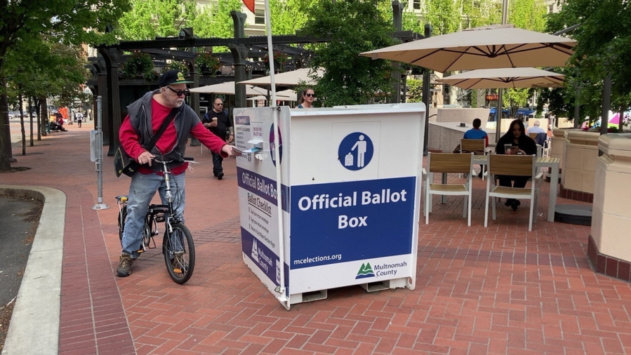 A voter drops off a ballot at a box in Pioneer Courthouse Square in Portland, Ore., Tuesday, May, 17, 2022. The state is holding its primary elections.