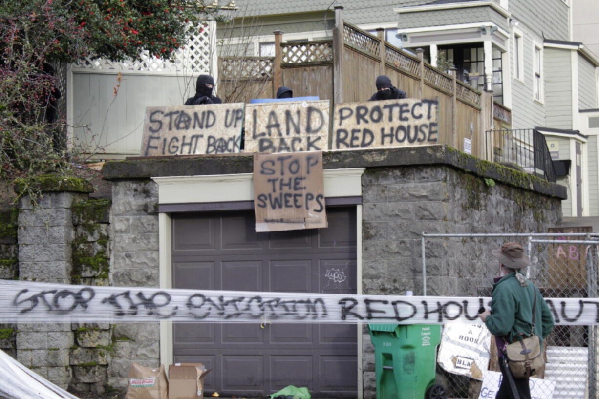 FILE - Masked protesters by an occupied home speak with a neighborhood resident opposed to their encampment and demonstration in Portland, Ore., on Dec. 9, 2020. Growing discontent over homelessness, crime and protests in Portland is driving interest in a pair of congressional primaries in the state.