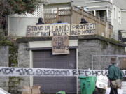 FILE - Masked protesters by an occupied home speak with a neighborhood resident opposed to their encampment and demonstration in Portland, Ore., on Dec. 9, 2020. Growing discontent over homelessness, crime and protests in Portland is driving interest in a pair of congressional primaries in the state.