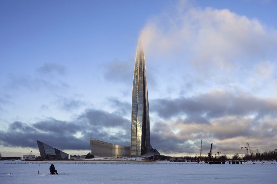 FILE- A man fishes on the ice of Finnish Gulf next to the business tower Lakhta Centre, the headquarters of Russian gas monopoly Gazprom covered by clouds in St. Petersburg, Russia, on Jan. 13, 2022.
