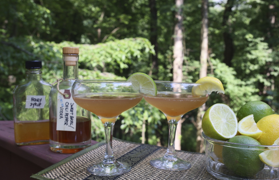 Cocktails containing alcohol and syrup infusions sit amid bottles and mixing accessories in Allison Park, Pa., on July 4, 2021. Alcohol and syrup infusions are growing in popularity and are relatively simple to incorporate into home bars.