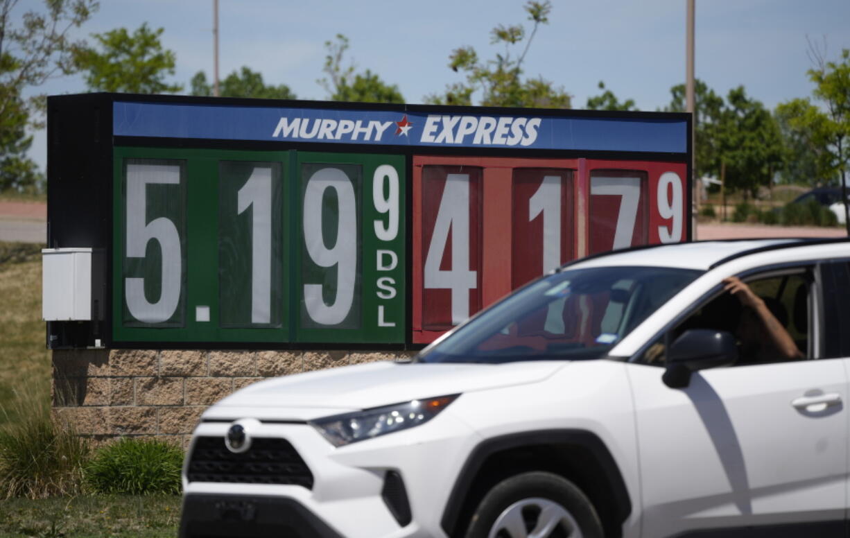 Gasoline prices are displayed outside a convenience store as a motorist drives by, Thursday, May 26, 2022, in Thornton, Colo. Experts are expecting a flush of travelers at airports and on the nation's byways during the long Memorial Day weekend, which marks the start of the summer travel season, in spite of high fuel costs.