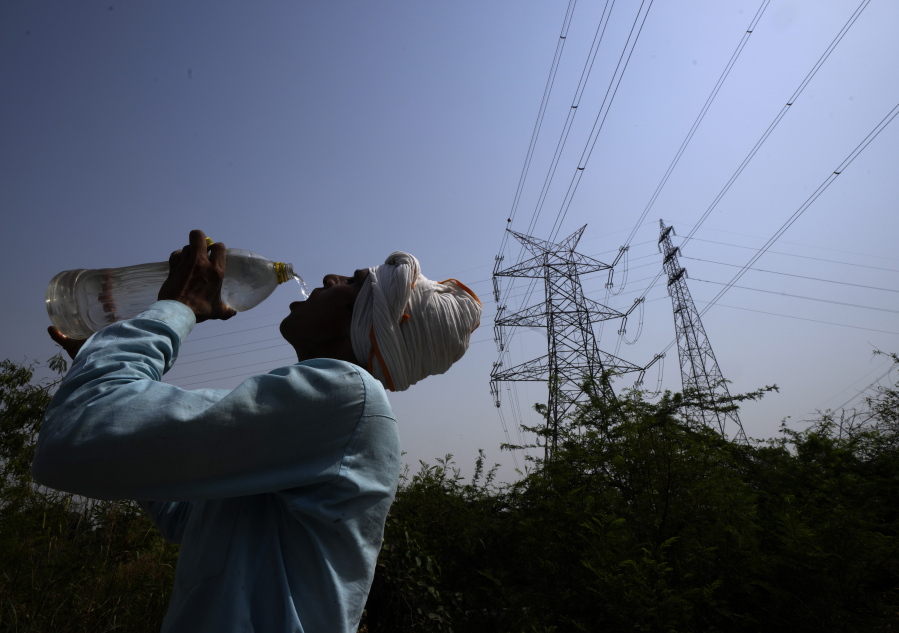 A workers quenches his thirst next to power lines as a heatwave continues to lashes the capital, in New Delhi, India, Monday, May 2, 2022. An unusually early and brutal heat wave is scorching parts of India, where acute power shortages are affecting millions as demand for electricity surges to record levels.