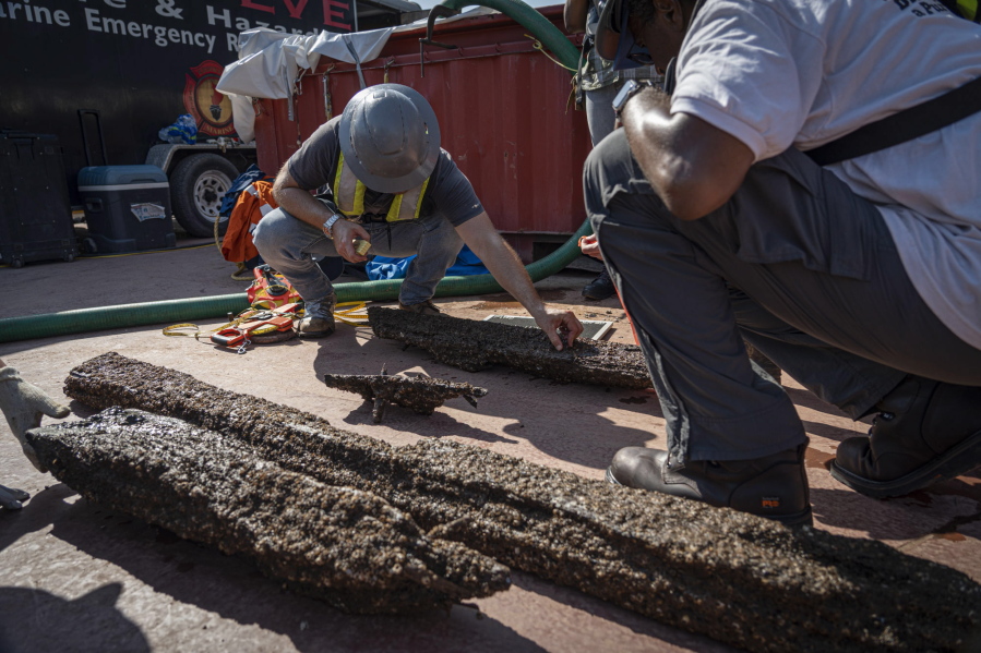 Members of the team assessing the sunken wreckage of the last U.S. slave ship, the Clotilda, are shown looking at timbers from the schooner near Mobile, Ala., on Wednesday, May 4, 2022. The ship was scuttled after arriving on the Gulf Coast more than 160 years ago.