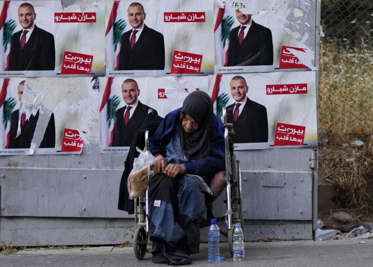 A homeless woman sits in front of campaign posters for a candidate in the upcoming parliamentary elections in Beirut, Lebanon, Monday, May 9, 2022. Given Lebanon's devastating economic meltdown, Sunday's parliament election is seen as an opportunity to punish the current crop of politicians that have driven the country to the ground. Yet a sense of widespread apathy and cynicism prevails, with many saying it is futile to expect change.