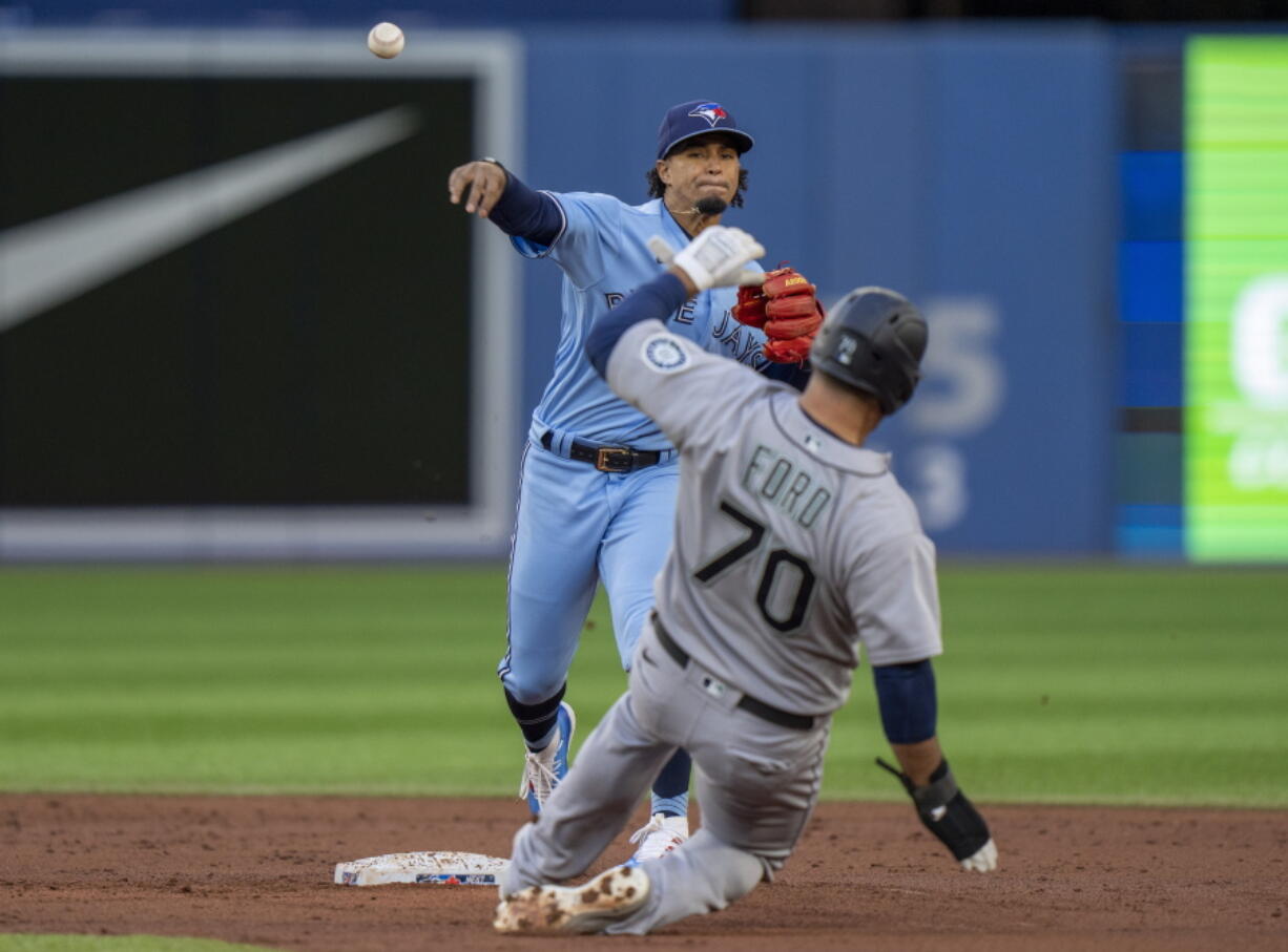 Toronto Blue Jays second baseman Santiago Espinal throws to first after forcing out Seattle Mariners' Mike Ford (70) during the second inning of a baseball game Tuesday, May 17, 2022, in Toronto. Steven Souza Jr. was out at first.