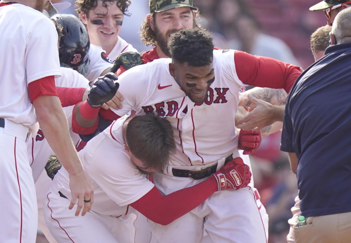 Boston Red Sox's Franchy Cordero, center, celebrates with teammates after hitting a grand slam in the tenth inning of a baseball game against the Seattle Mariners, Sunday, May 22, 2022, in Boston. The Red Sox won 8-4.