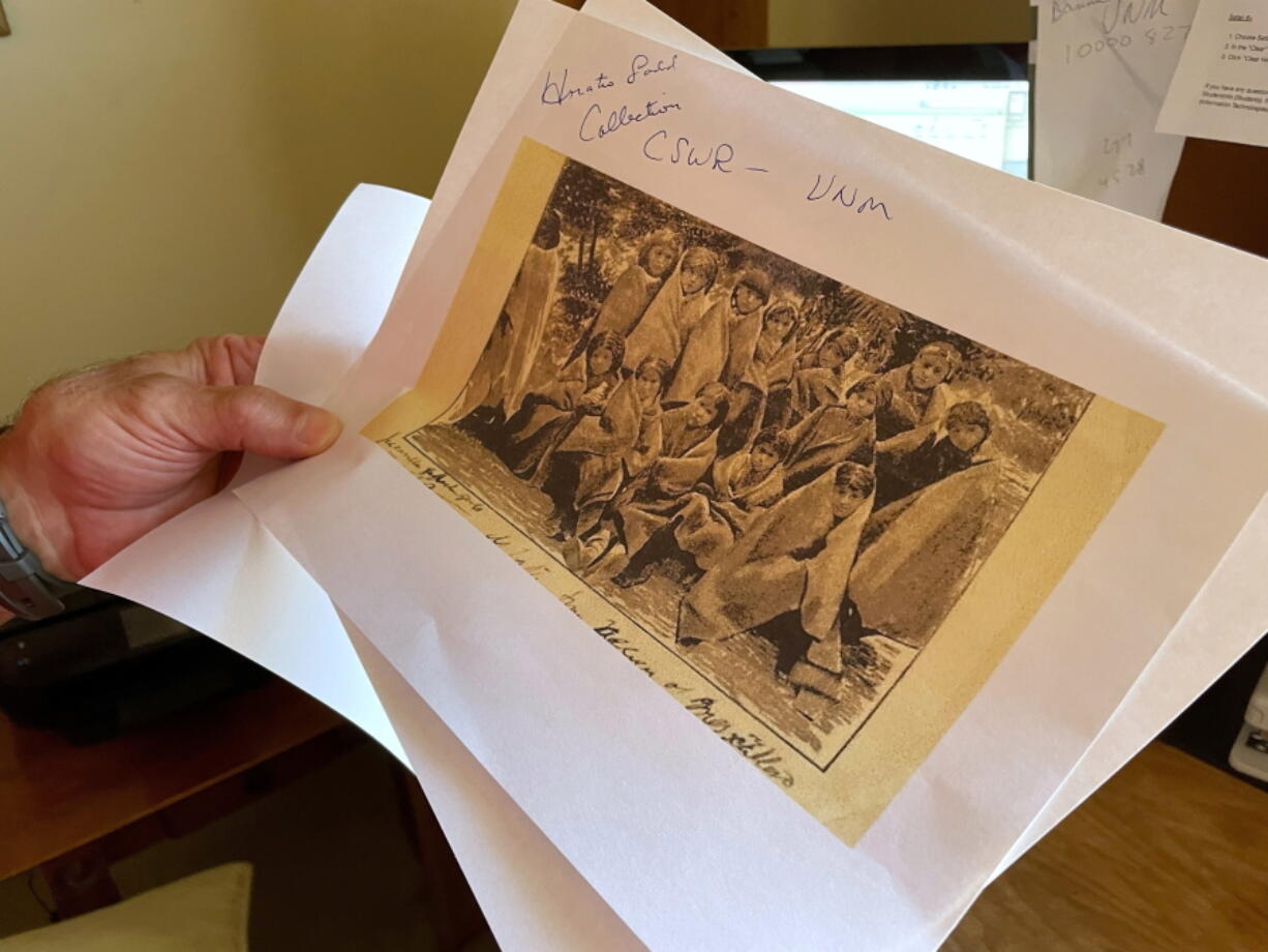 FILE - In this July 8, 2021, photo, adjunct history professor and research associate Larry Larrichio holds a copy of a late 19th century photograph of pupils at an Indigenous boarding school in Santa Fe during an interview in Albuquerque, N.M.  A new federal report on the legacy of boarding schools for Native Americans underscores how closely the U.S. government collaborated with churches to Christianize the Indigenous population as part of a project to sever them from their culture, their identities and ultimately their land. The Department of the Interior report, released Wednesday, May 11, 2022, says the federal government provided funding and other support to religious boarding schools for Native children in the 19th and early 20th centuries to an extent that normally would have been prohibited by bans on the use of federal funds for religious schools.