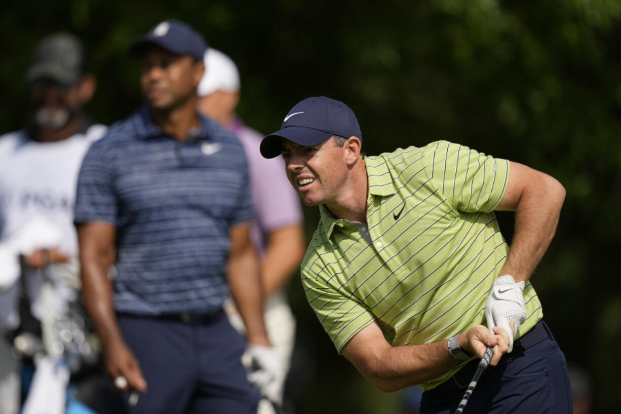 Rory McIlroy, of Northern Ireland, watches his tee shot as Tiger Woods looks on, on the 17th hole during the first round of the PGA Championship golf tournament, Thursday, May 19, 2022, in Tulsa, Okla.