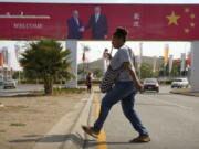 FILE - A woman crosses the street near a billboard commemorating the state visit of Chinese President Xi Jinping in Port Moresby, Papua New Guinea, Nov. 15, 2018. China wants 10 small Pacific nations to endorse a sweeping agreement covering everything from security to fisheries in what one leader warns is a "game-changing" bid by Beijing to wrest control of the region.