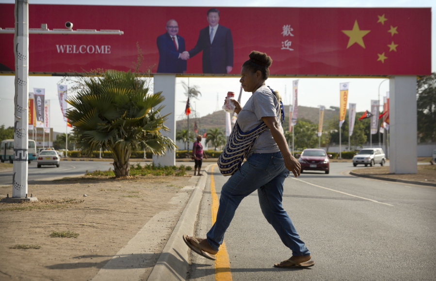 FILE - A woman crosses the street near a billboard commemorating the state visit of Chinese President Xi Jinping in Port Moresby, Papua New Guinea, Nov. 15, 2018. China wants 10 small Pacific nations to endorse a sweeping agreement covering everything from security to fisheries in what one leader warns is a "game-changing" bid by Beijing to wrest control of the region.