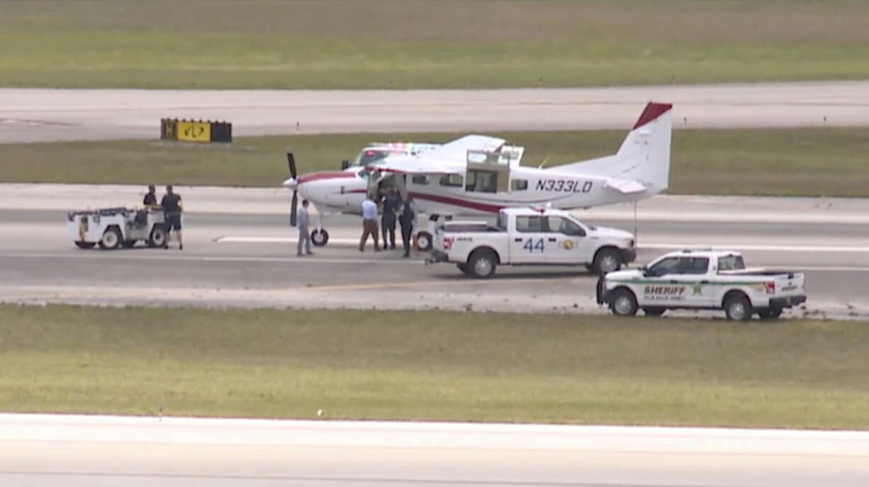 In this still image from video by WPTV shows emergency personnel surrounding a Cessna plane at Palm Beach International Airport Tuesday, May 10, 2022, in West Palm Beach, Fla. A passenger with no flying experience was able to land the plane safely with help of air traffic controllers after the pilot was too sick to handle the controls.