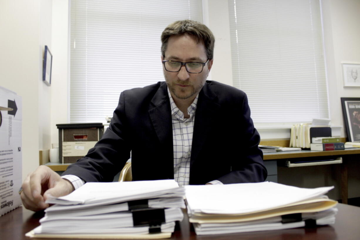 Carl Macpherson, executive director at Metropolitan Public Defender, examines the file in a double murder case that was recently pushed back for trial in his office in Portland, Ore., on May 5, 2022. Macpherson says his firm of 90 public defenders recently stopped taking certain types of new criminal cases for a month in two local courts because they had so many cases that the attorneys were violating their ethical obligations to clients. A post-pandemic glut of delayed cases has exposed shocking constitutional landmines impacting defendants and crime victims alike in Oregon, where an acute shortage of public defenders has even led judges to dismiss serious cases.