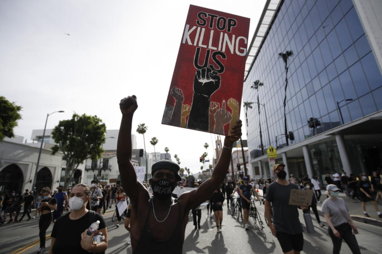 FILE - A protester carries a sign in the Hollywood area of Los Angeles on June 1, 2020, during demonstrations after the killing of George Floyd which sparked calls for a racial reckoning to address structural racism that has created longstanding inequities impacting generations of Black Americans. Floyd's murder, along with a series of killings of other Black Americans wrought a heavy emotional and mental toll on Black communities that have already been burdened and traumatized by centuries of oppressive systems and racist practices.