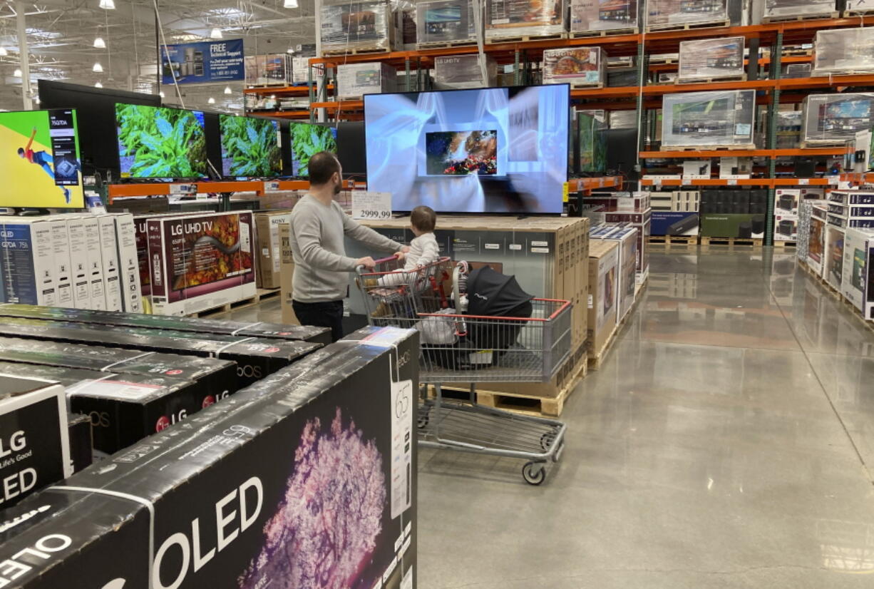 FILE - A shopper pushes a child in a cart while browsing big-screen televisions on display in the electronics section of a Costco warehouse, Tuesday, March 29, 2022, in Lone Tree, Colo.  U.S. retail sales rose 0.9% in April, a solid increase that underscores Americans' ability to keep ramping up spending even as inflation persists at nearly a 40-year high. The Commerce Department said Tuesday, May 17,  that the increase was driven by greater sales of cars, electronics, and at restaurants. Even adjusting for inflation, which was 0.3% on a monthly basis in April, sales increased.
