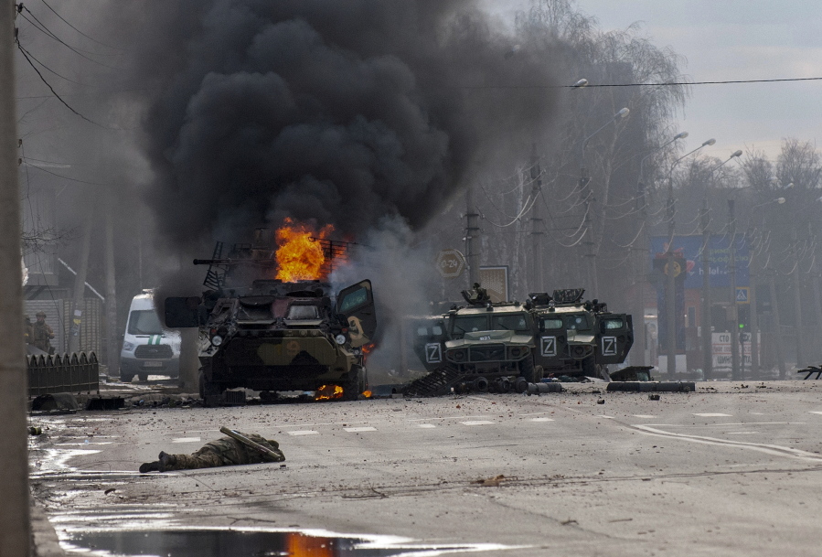 FILE - A Russian armored personnel carrier burns amid damaged and abandoned light utility vehicles after fighting in Kharkiv, the country's second-largest city in Ukraine, Feb. 27, 2022. Three months after it invaded Ukraine hoping to overtake the country in a blitz, Russia has bogged down in what increasingly looks like a war of attrition with no end in sight.
