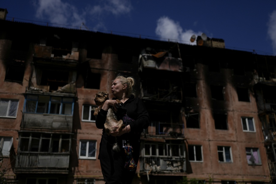 Olga Chernenko, 51, holds her dog Casper outside her home damaged by attacks in Irpin, on the outskirts of Kyiv, Ukraine, Thursday, May 26, 2022. Chernenko says she walks past her burned-down house often because that is where she lived for 48 years, almost her whole life, and that she hopes Russia President Vladimir Putin will be punished for what he did.
